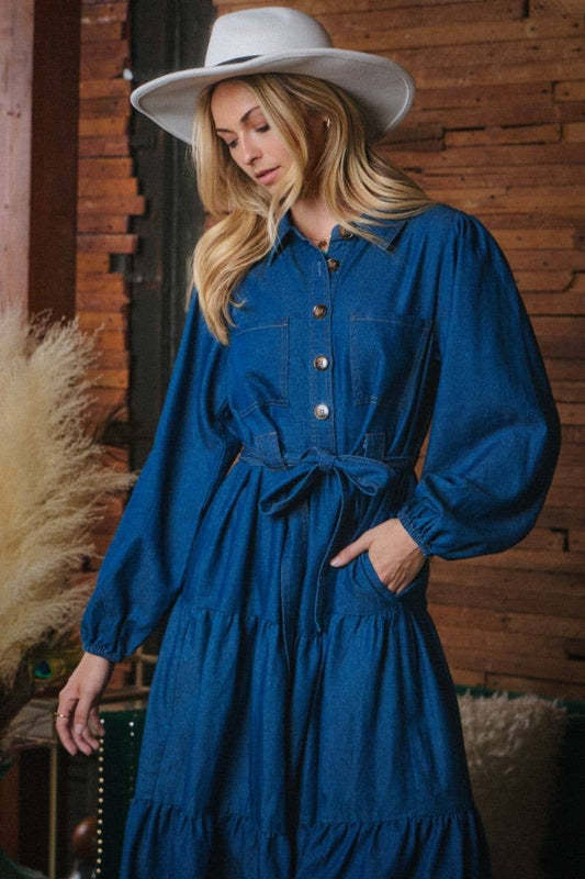 Woman wearing a blue denim dress and white hat indoors with wooden wall background