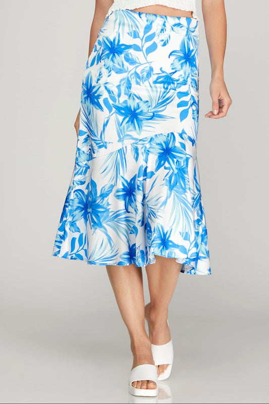 Woman wearing a white top and blue floral skirt on a gray background