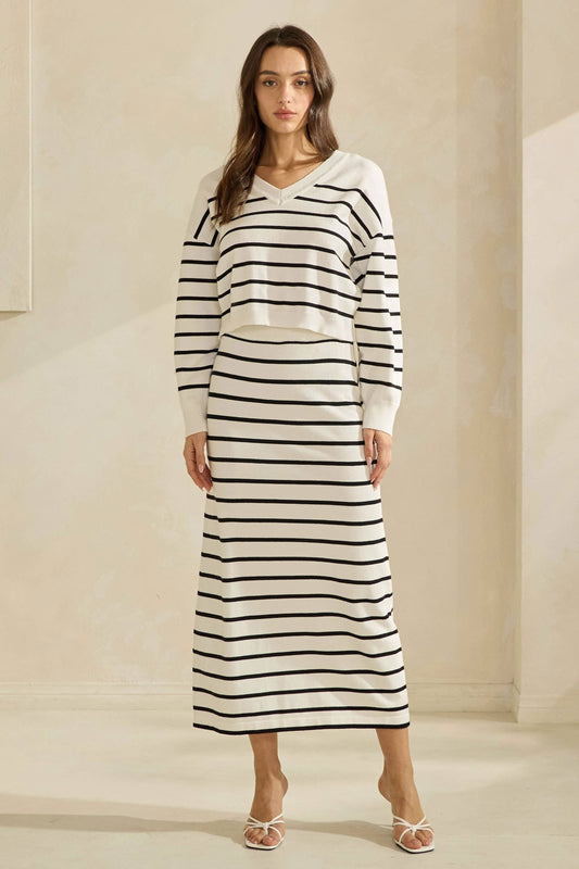 Woman wearing a long black and white striped dress against a neutral background