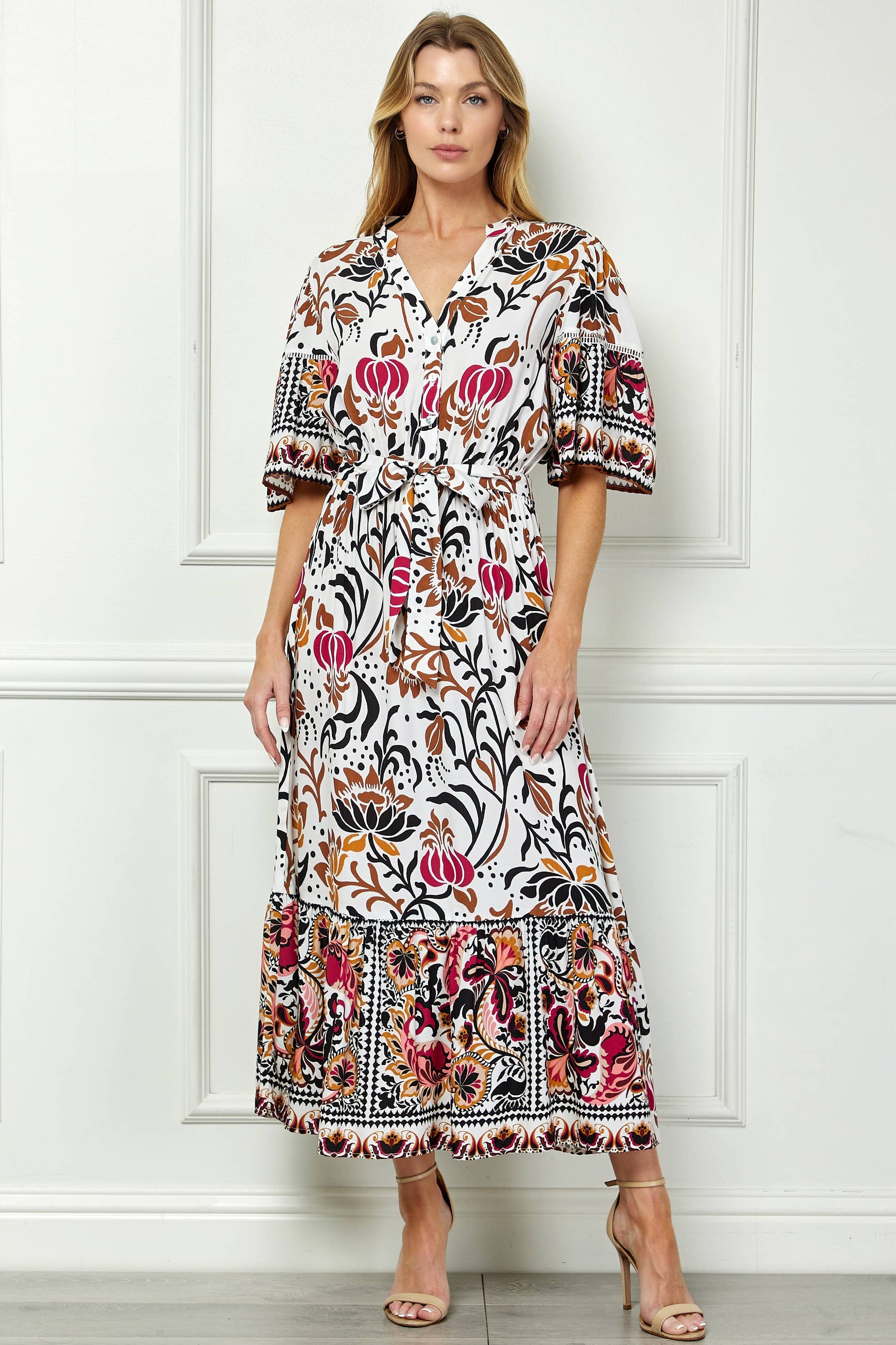 Woman wearing a floral dress against a white paneled wall