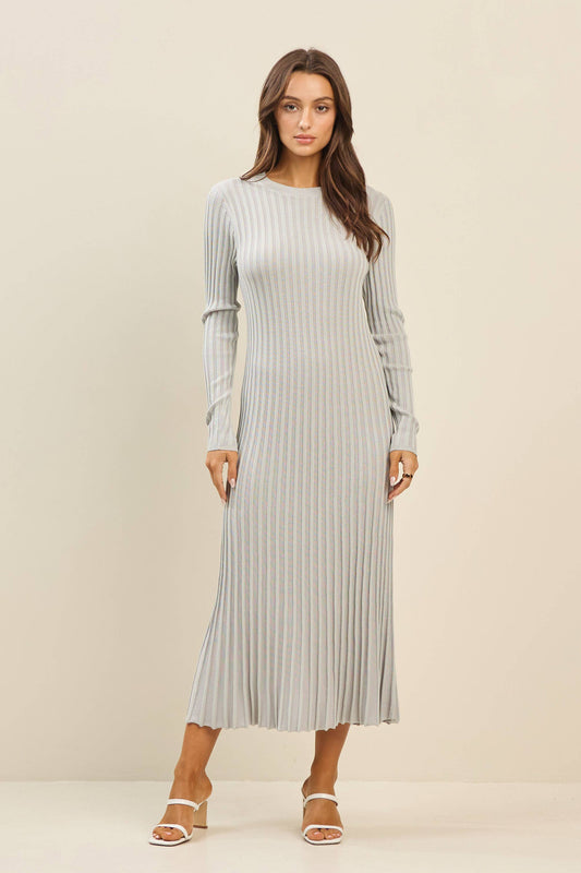 Woman wearing a long, light gray ribbed dress against a beige background