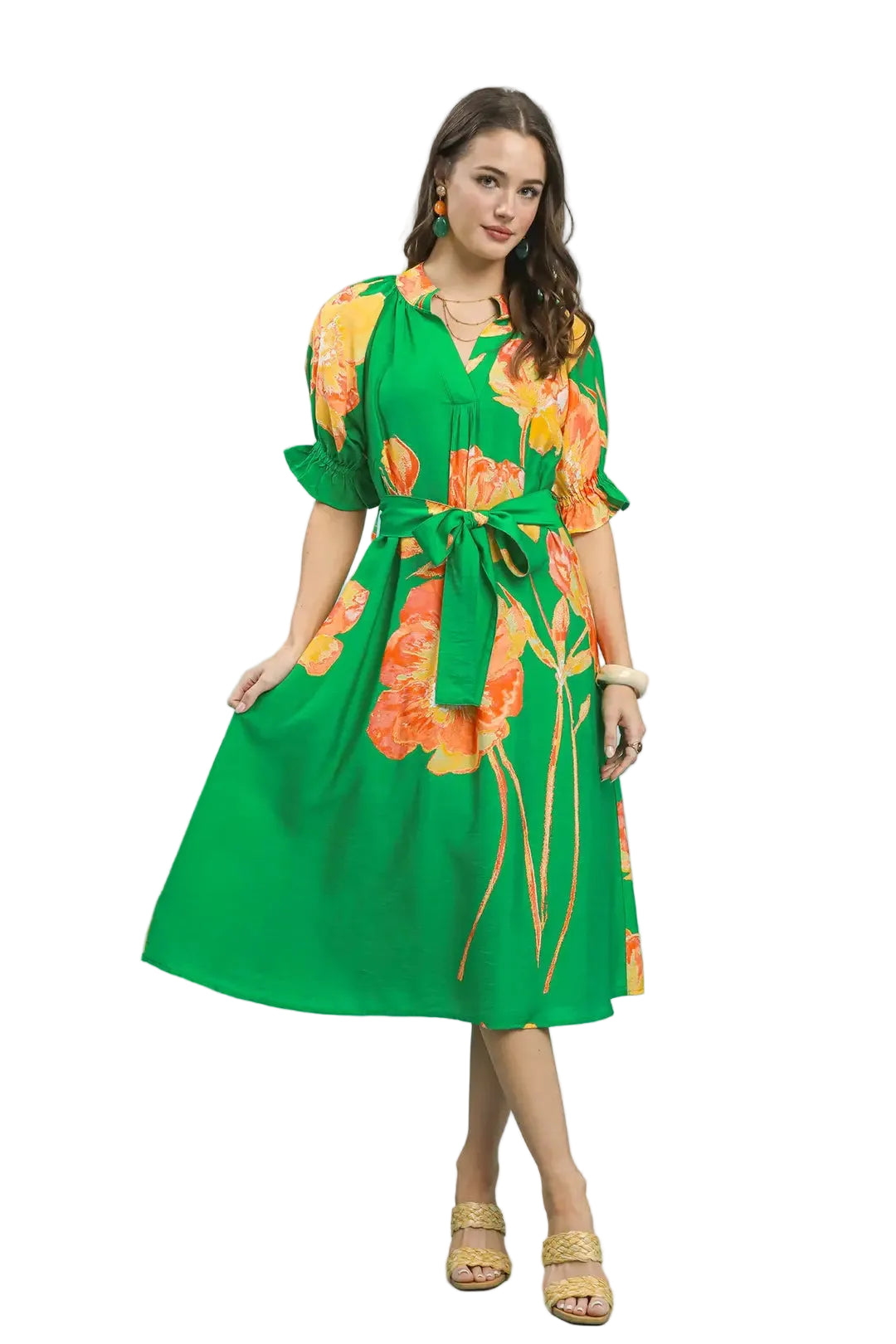 Woman wearing a green dress with orange floral patterns on a light blue background